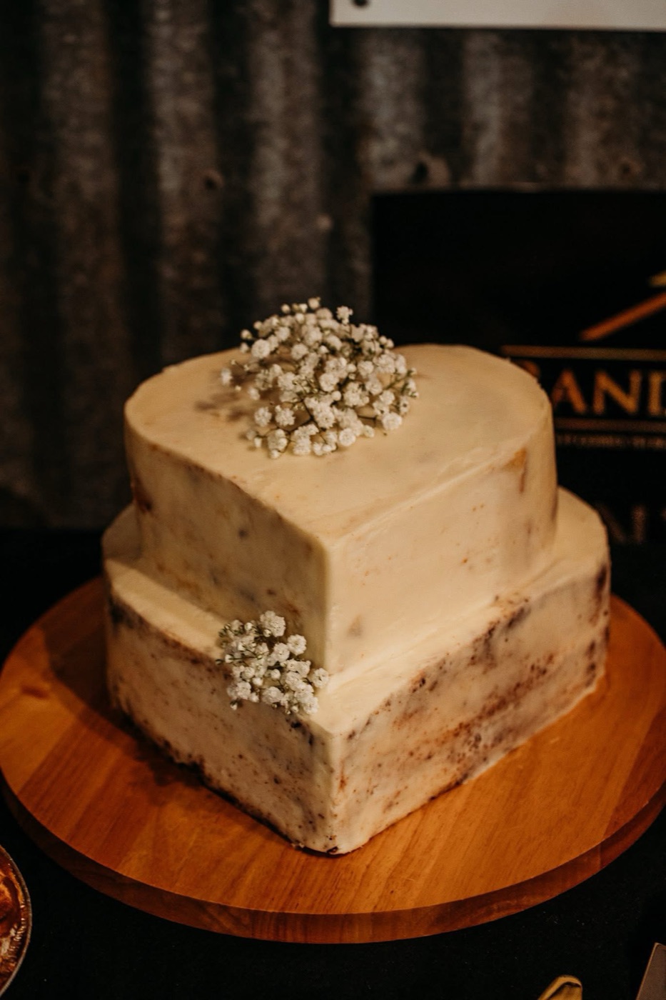 Two-tier naked vanilla wedding cake trimmed with sprigs of baby’s breath