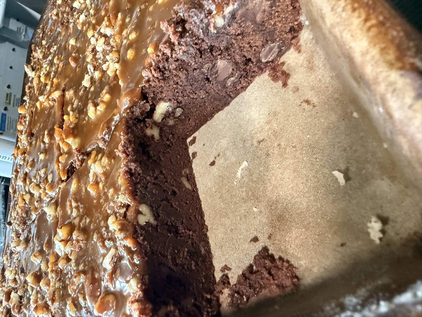 Pan of fudgy turtle brownies topped with caramel and chopped pecans